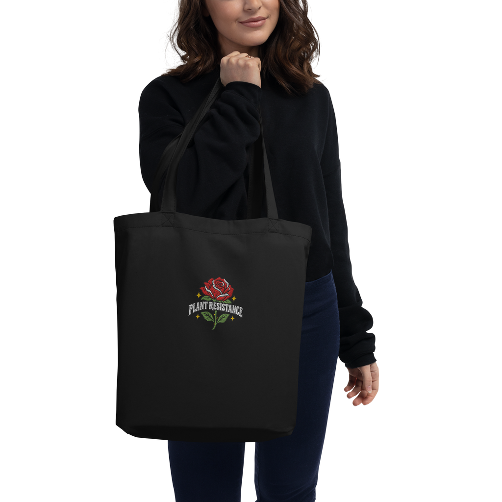 Black organic cotton tote bag with embroidered Plant Resistance rose design. Schwarze Bio-Baumwolltasche mit gesticktem Plant Resistance Rosen-Design.