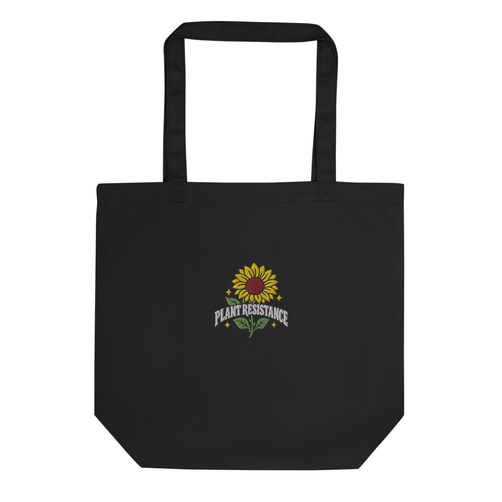 Black organic cotton tote bag with embroidered Plant Resistance sunflower design. Schwarze Bio-Baumwolltasche mit gesticktem Plant Resistance Sonnenblumen-Design.