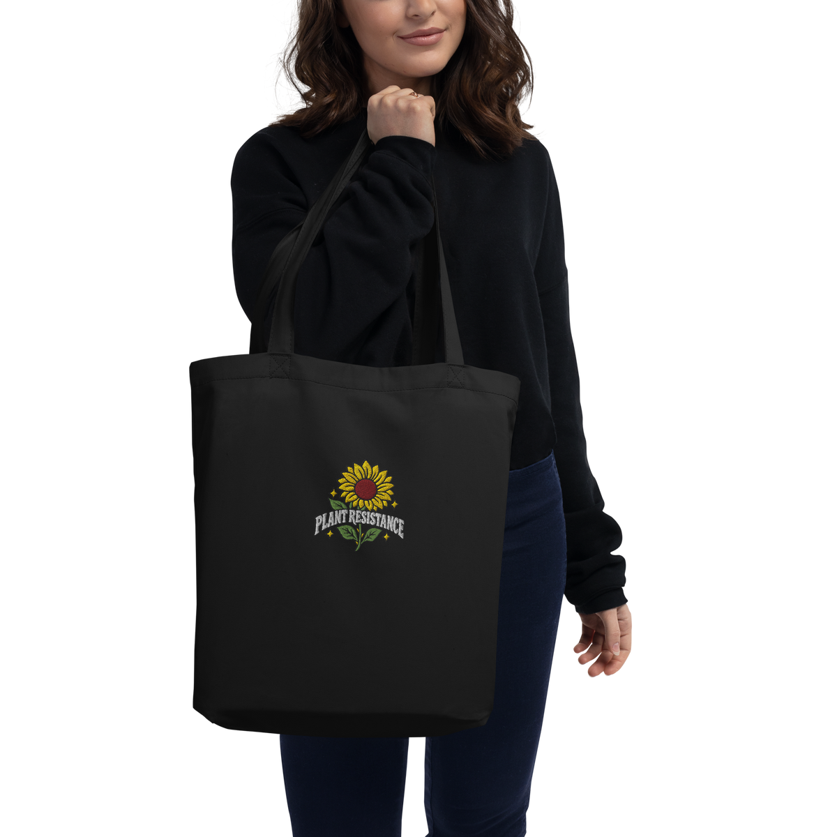 Black organic cotton tote bag with embroidered Plant Resistance sunflower design. Schwarze Bio-Baumwolltasche mit gesticktem Plant Resistance Sonnenblumen-Design.