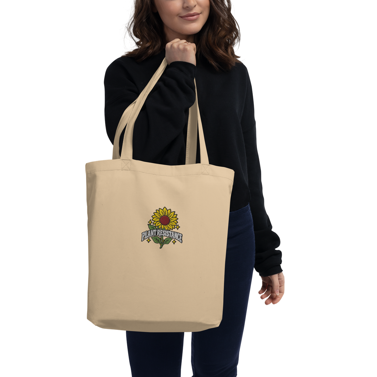 Black organic cotton tote bag with embroidered Plant Resistance sunflower design. Bio-Baumwolltasche mit gesticktem Plant Resistance Sonnenblumen-Design.